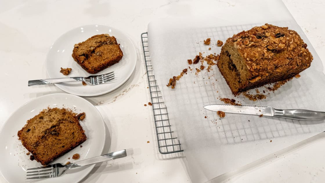 Two slices of my Spiced Olive Oil Banana Bread Recipe with a Walnut Streusel next to the loaf on parchment paper lined cooling rack