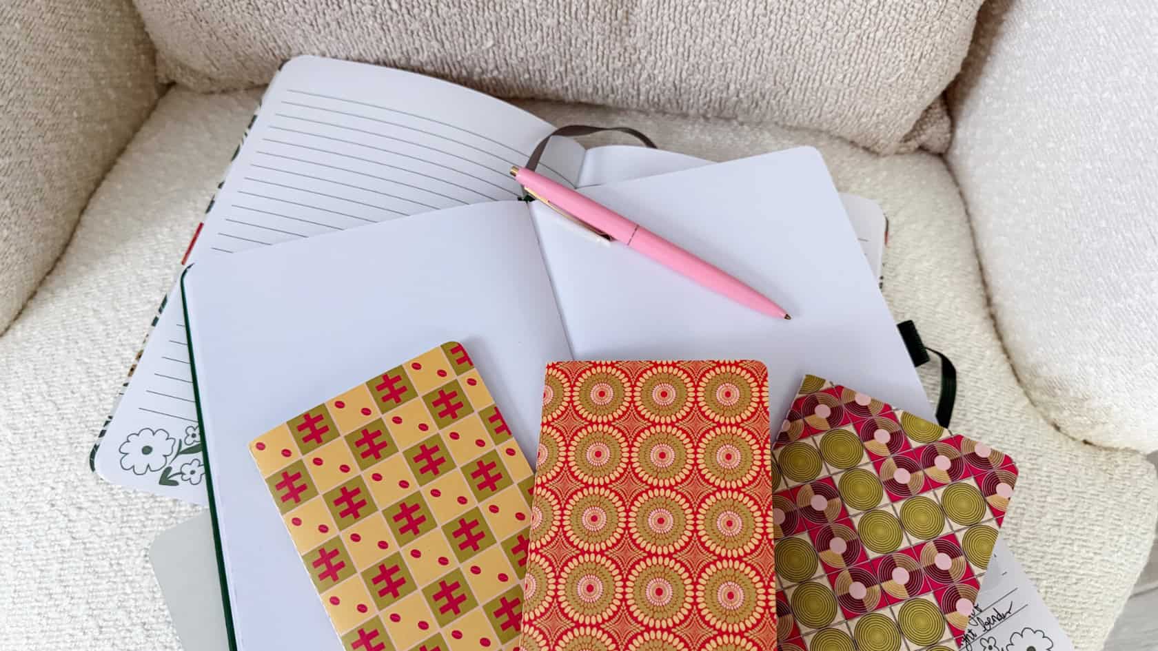 A flatlay of a minimalist journal and pen on a cozy reading chair