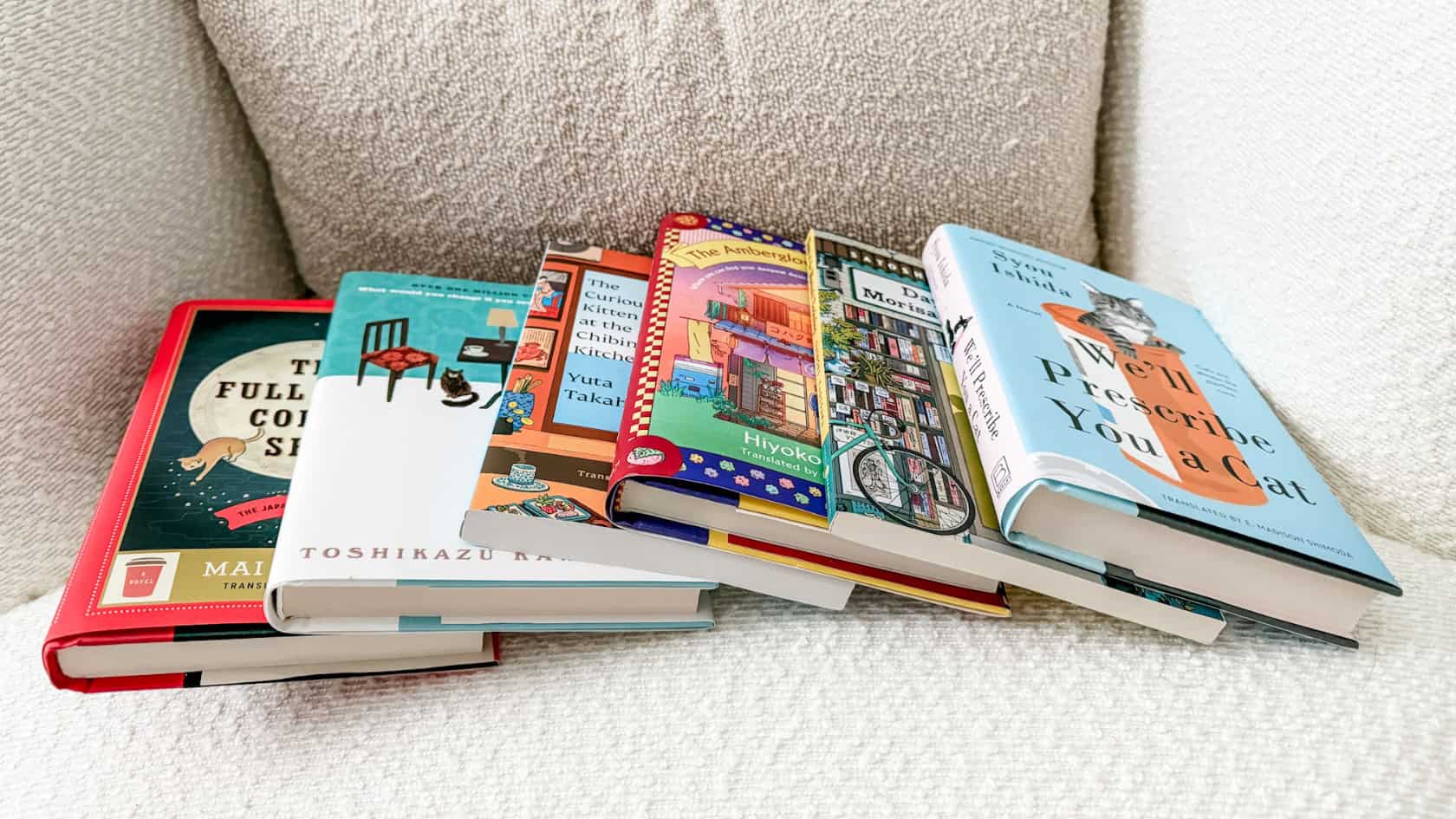 An angled photo of a cozy reading stack of healing Japanese comfort fiction books