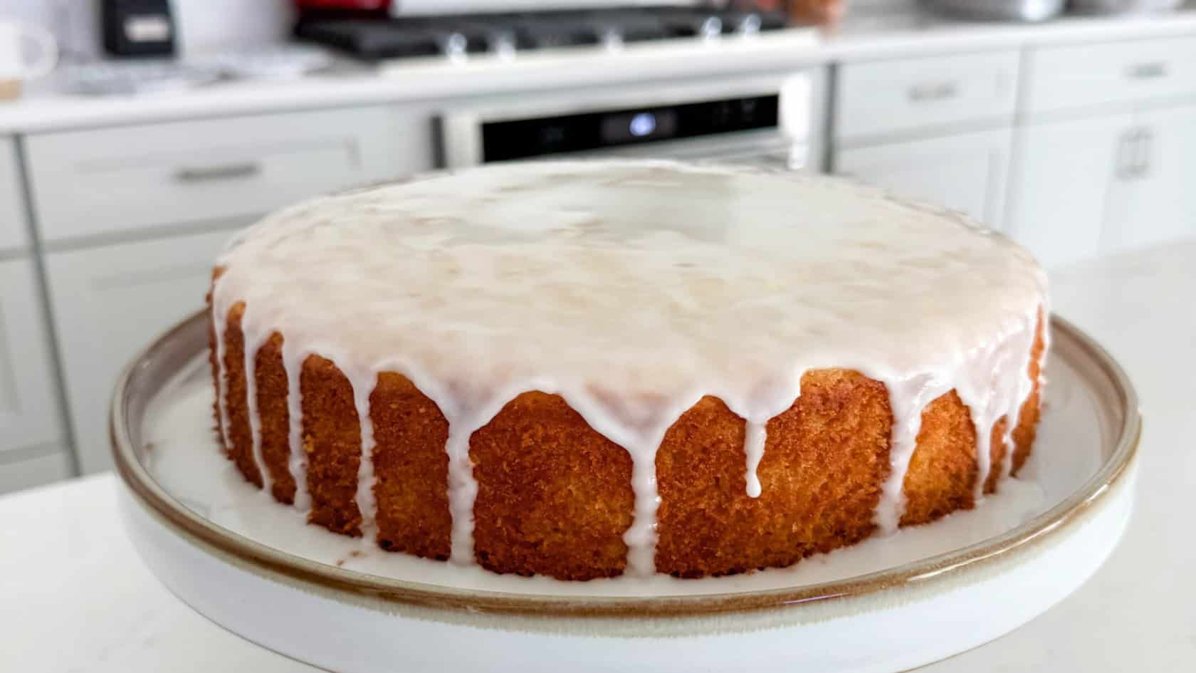Lemon Olive Oil Cake on a cake stand in my kitchen with my stove in the background