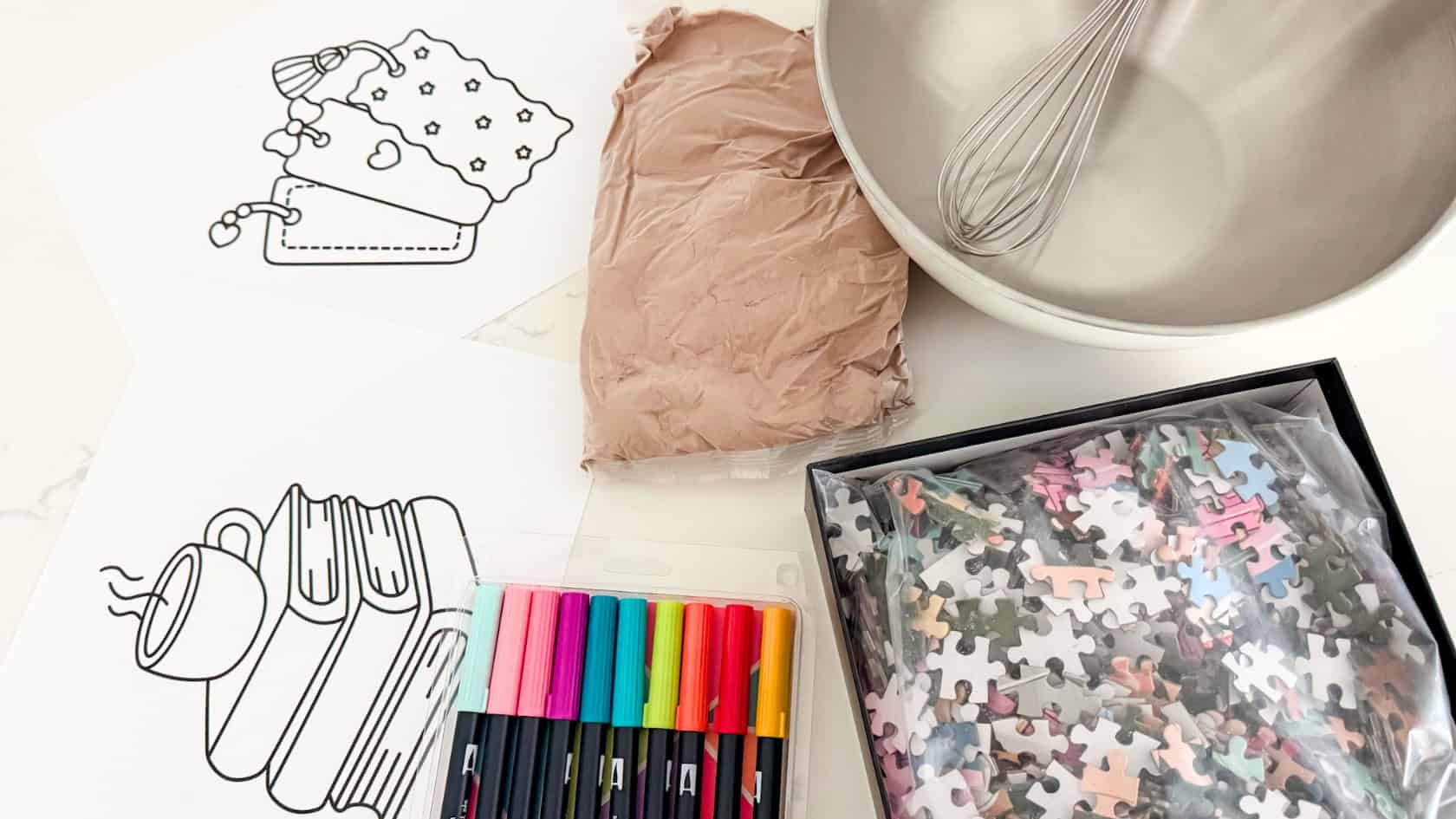 cozy at home date night setup with brownie mix for baking, bowl and whisk, jigsaw puzzles, and adult coloring pages
