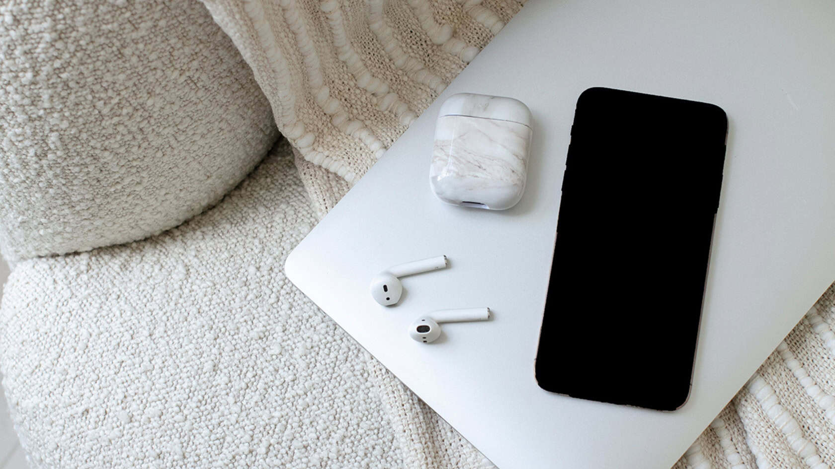 Lock screen iPhone on top of a closed laptop with headphones during a digital detox