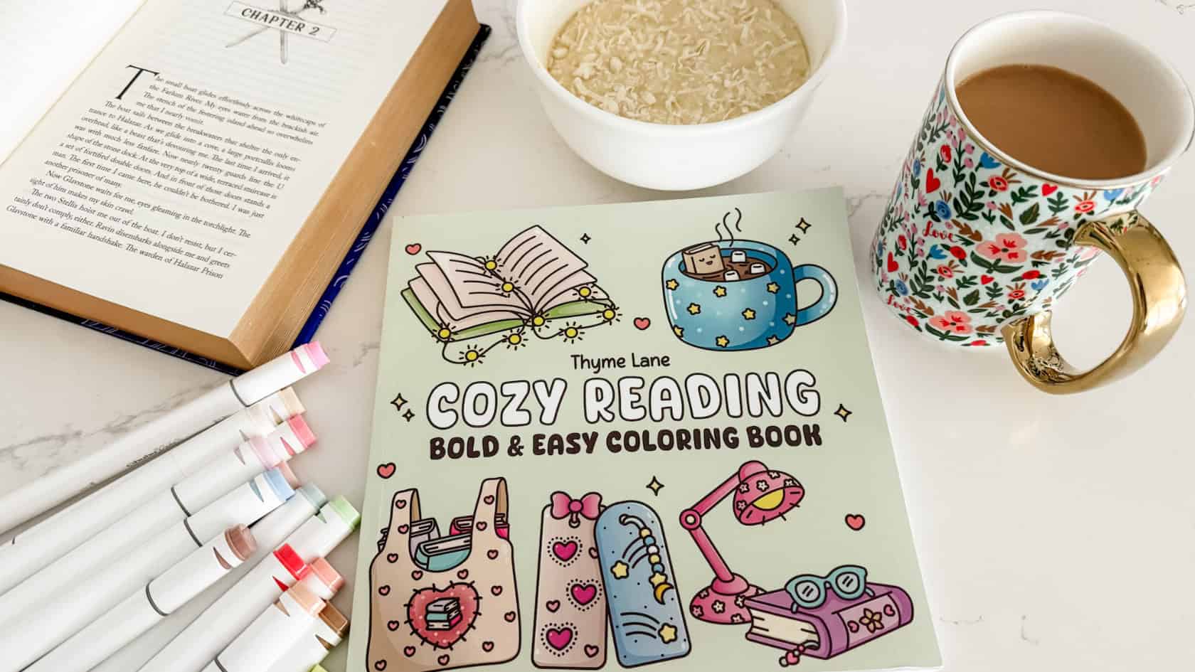 my soft week menu cozy setup with my cozy reading coloring book with colored markers, bowl cake, coffee, and fantasy book