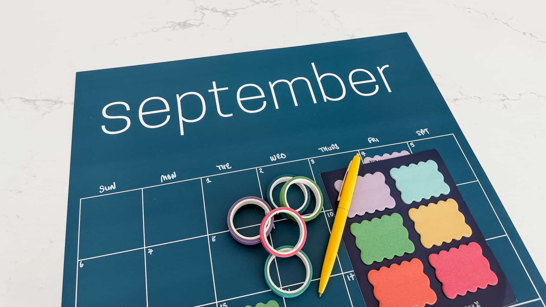 Flatlay of end-of-summer routine reset with calendar planner, coffee, pen, sticky notes details