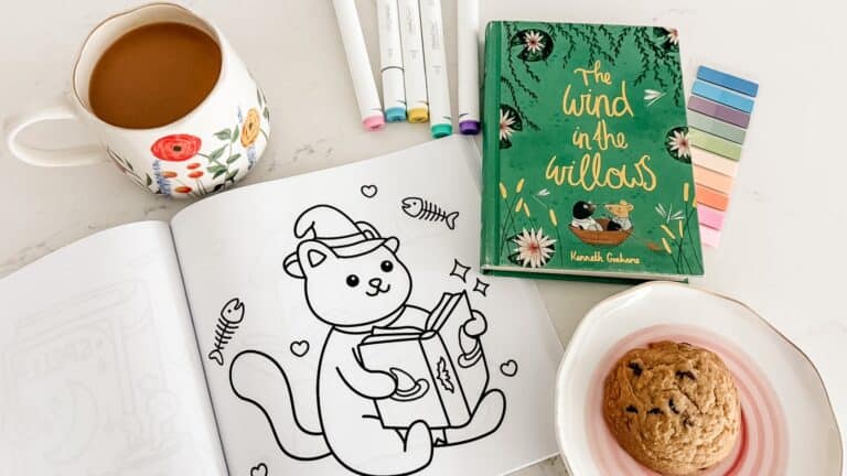 soft week menu cozy setup with a page from Bookish Halloween coloring book, markers, coffee, cookie, and The Wind in the Willows